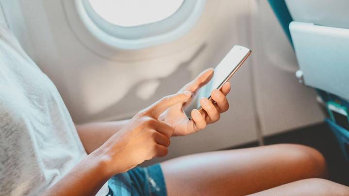飞机乘客斑点女人坐在他们面前，在阅读文本后有互联