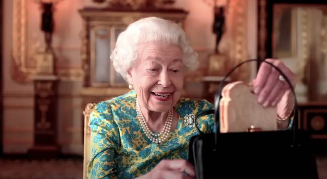 在短剧中，女王颊上从手提包中抽出自己的果酱三明治。学分：YouTube/王室/ BBC