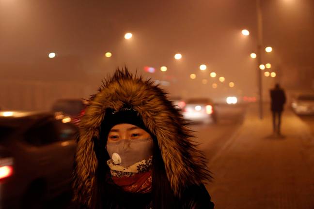 居民在外面戴口罩，以防止吸入污染的空气。信用：Alamy“loading=