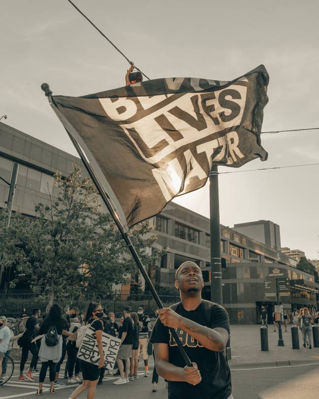 抗议者挥舞着“黑人生命物质”的旗帜。（信用：Unplash/Clay Banks）