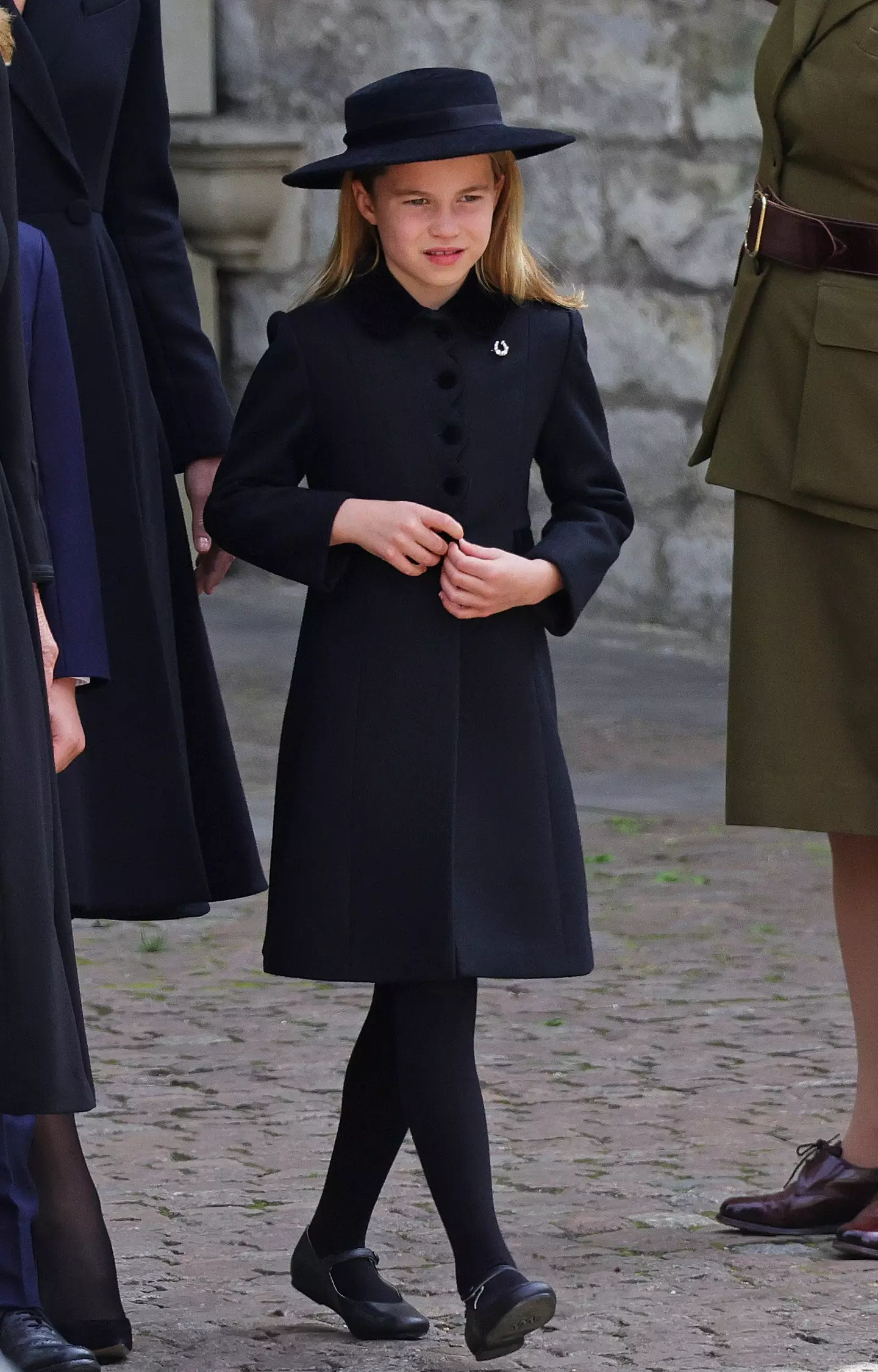 Princess Charlotte, seen wearing a horseshoe-shaped broach, walked behind the coffin with her family.
