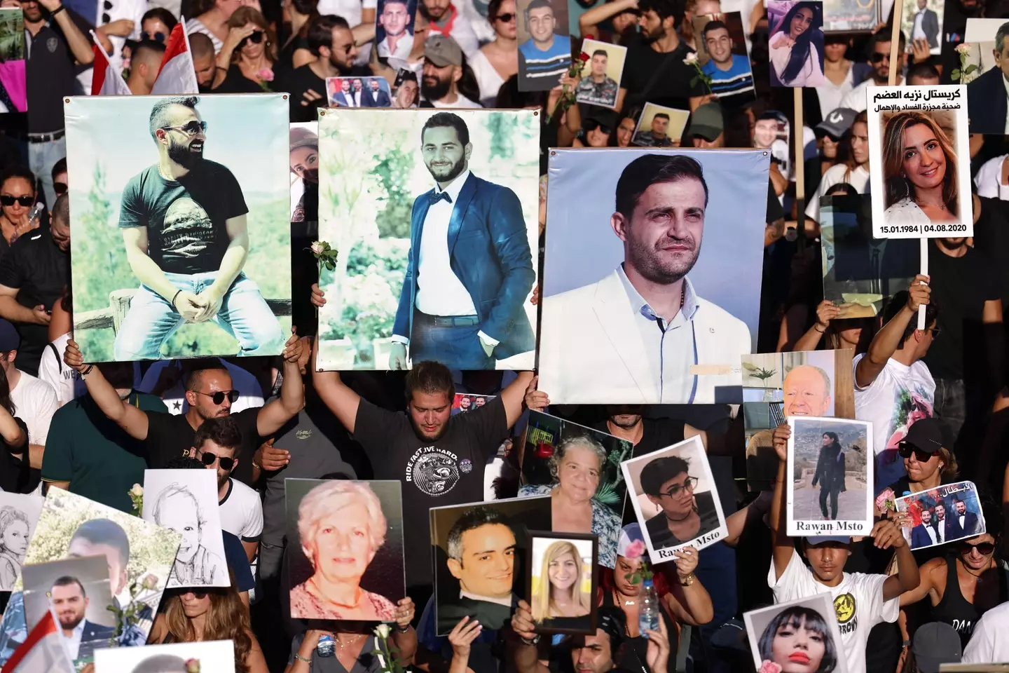 People hold up images of those killed in the explosion on its third anniversary. (JOSEPH EID/AFP via Getty Images)
