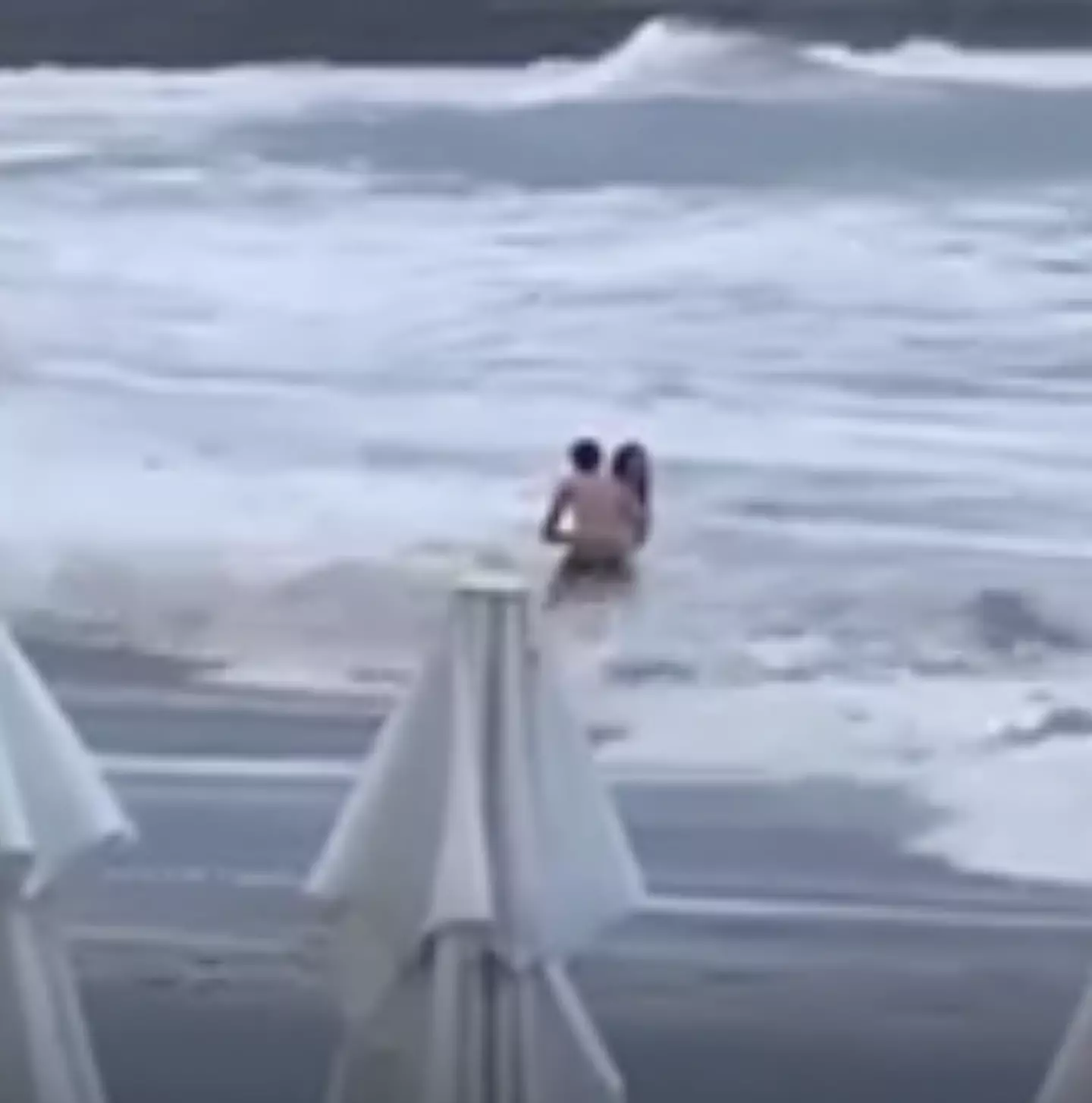 The couple were seen embracing before the woman was swept out to sea. (Newsflash)