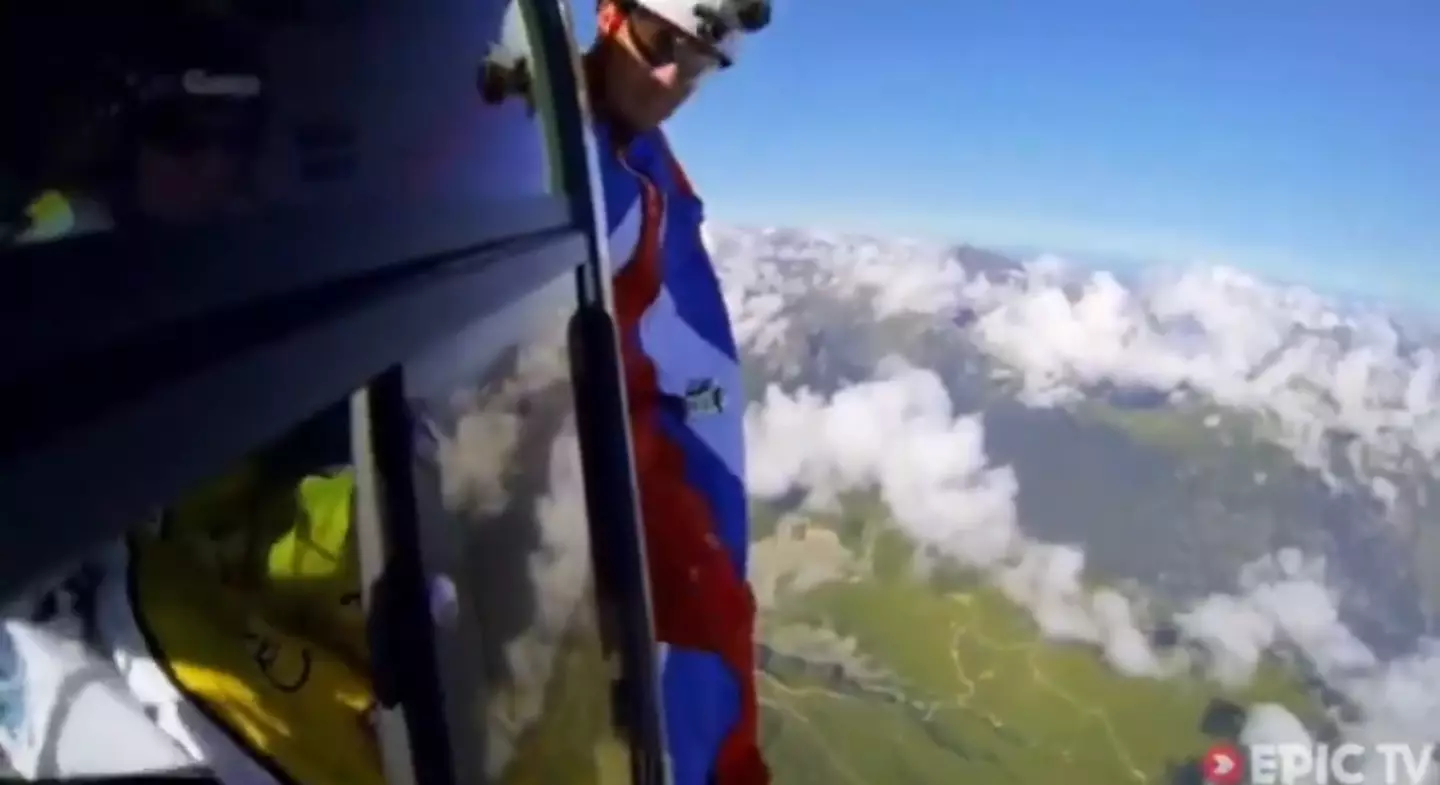 Mark Sutton in his blue and red wingsuit with reflective sunglasses stands on the edge of the chopper, mere seconds before his death. (Epic TV)
