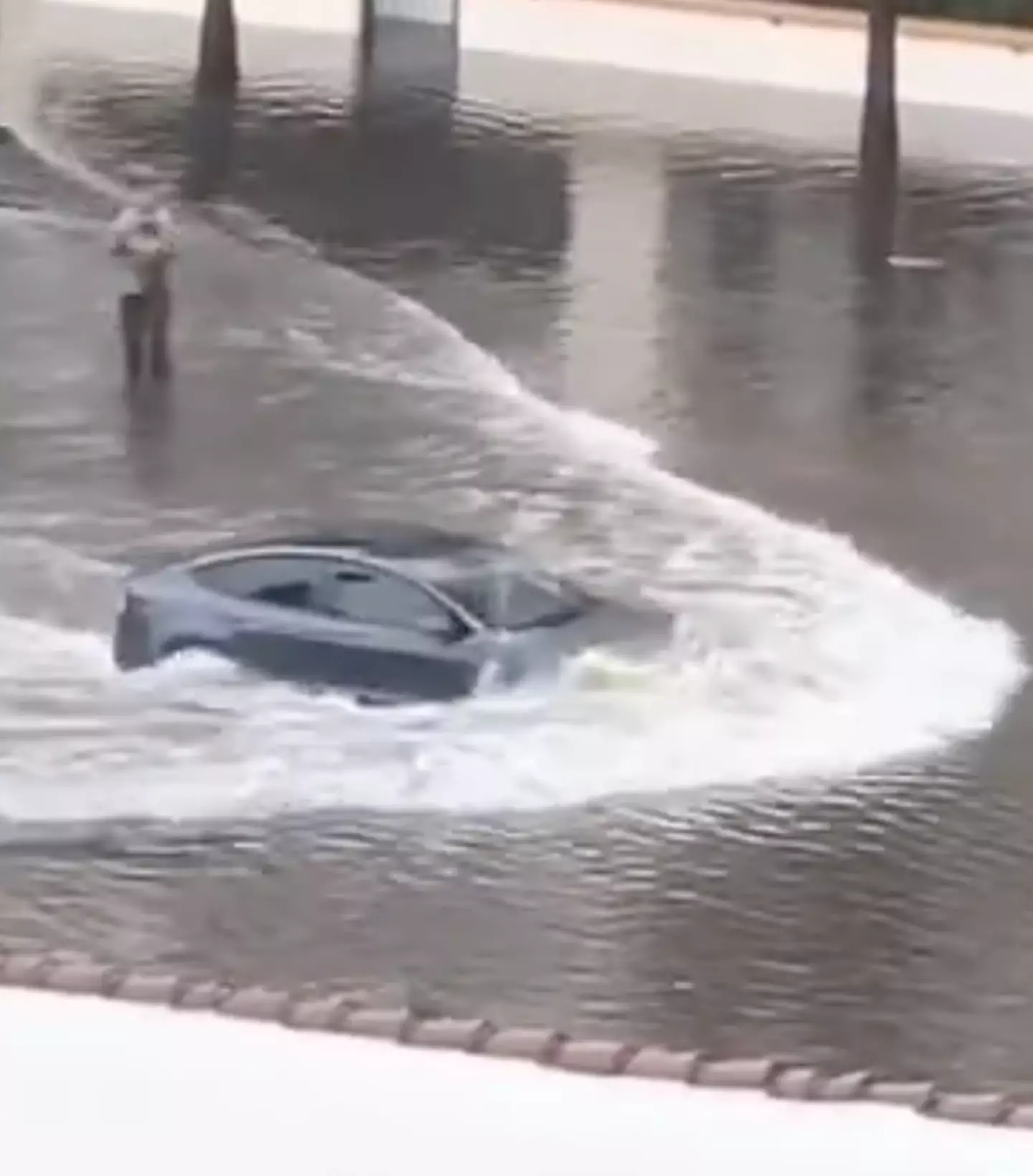 The Tesla driver is almost fully submerged in the flooded water / @‌NTFTWX / X