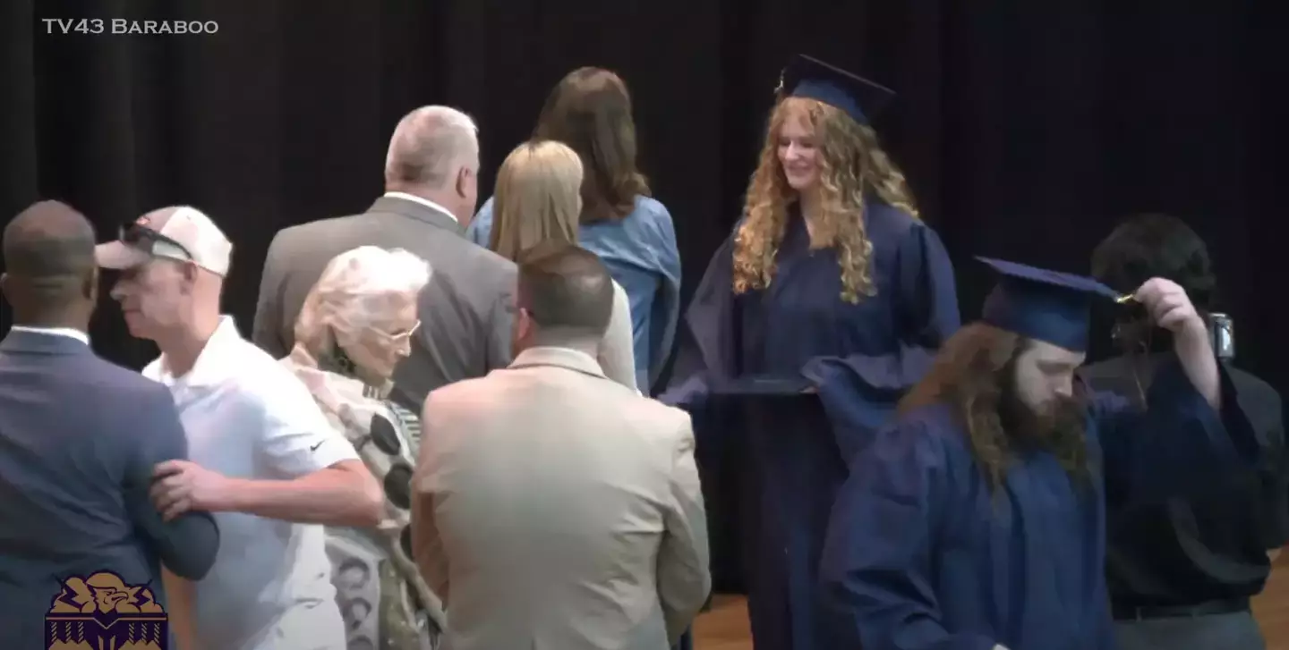 She was being handed her diploma while her dad got onto the stage and pushed a man away. (MAX TV - BARABOO)