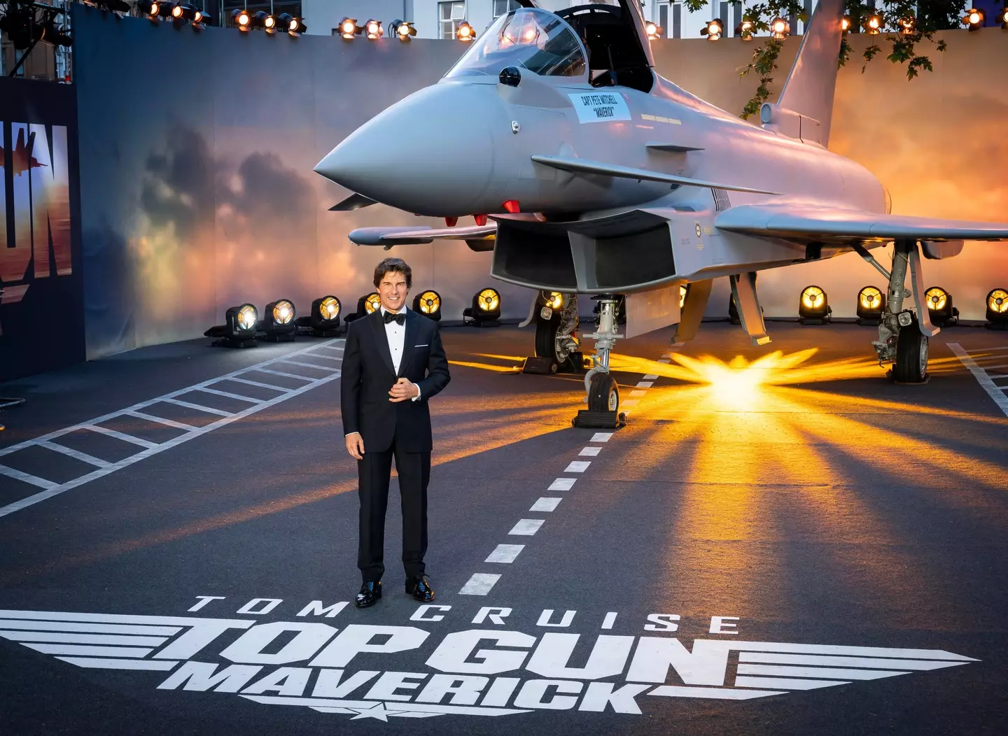 Tom Cruise stands in front of a fighter jet as he attends the Royal performance of Top Gun: Maverick.
