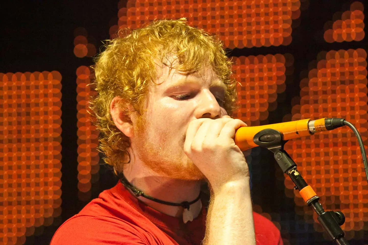 Ed Sheeran performing live on stage, where he may or may not be letting out a cheeky fart.