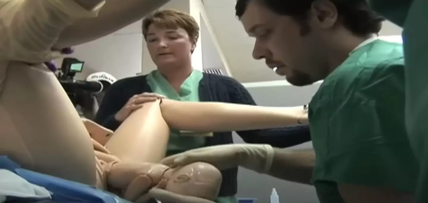 The students can be seen delivering the robot baby in the manner that they would be expected to with a real child. (YouTube/Discovery)