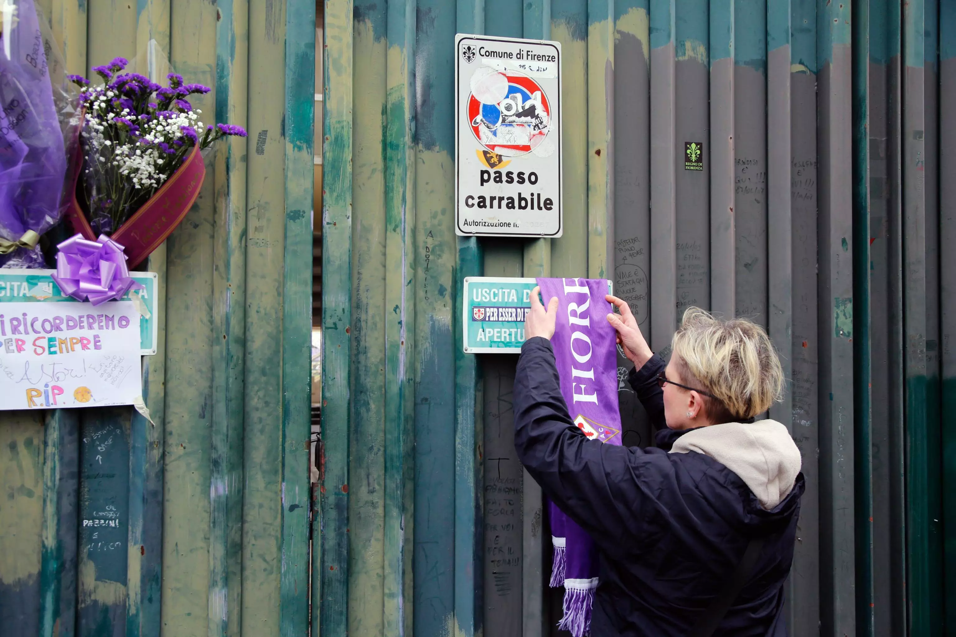 A woman attaches a scarf outside the Artemio Franchi stadium. Image: PA Images