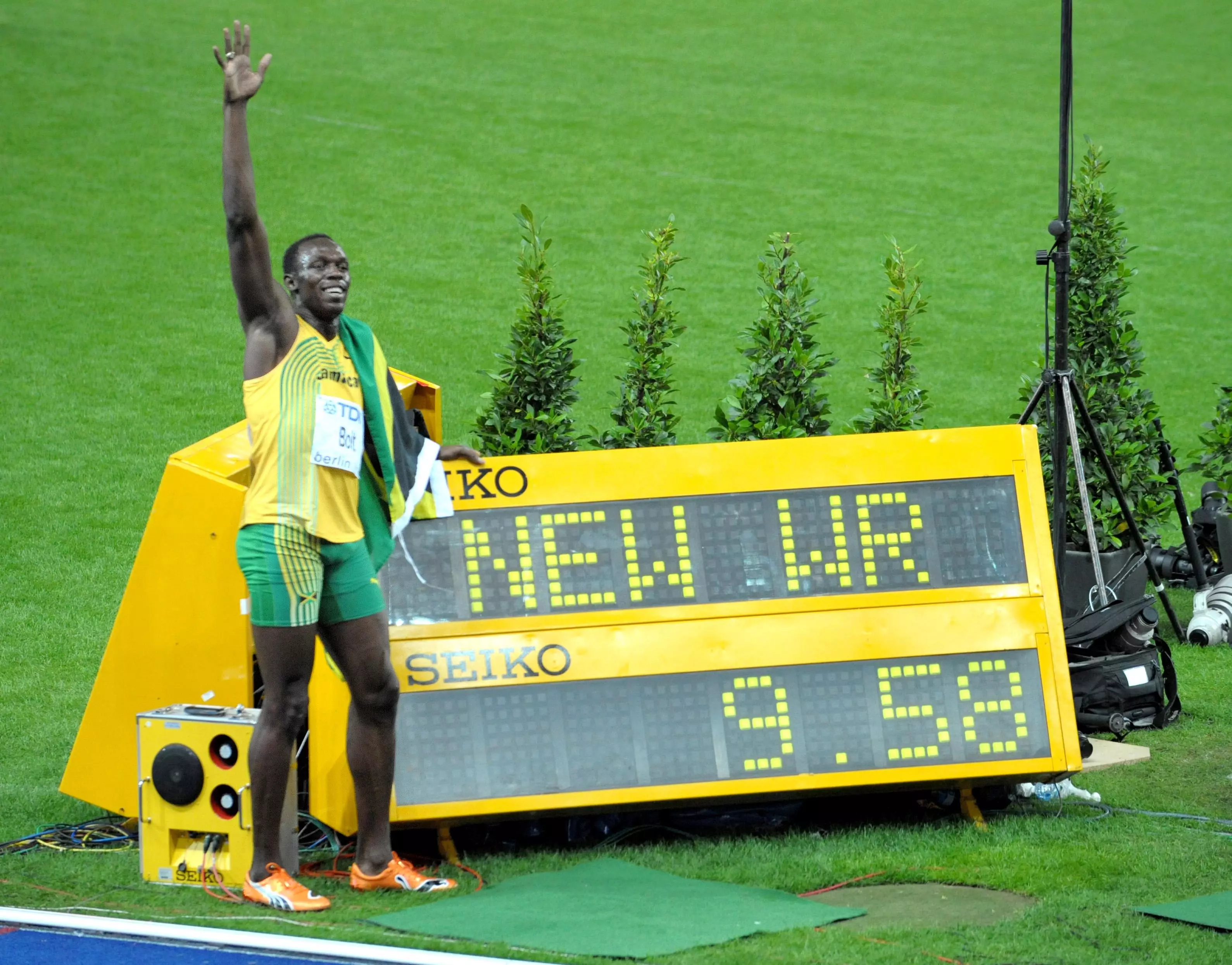 Bolt poses next to the screen showing his world record time.