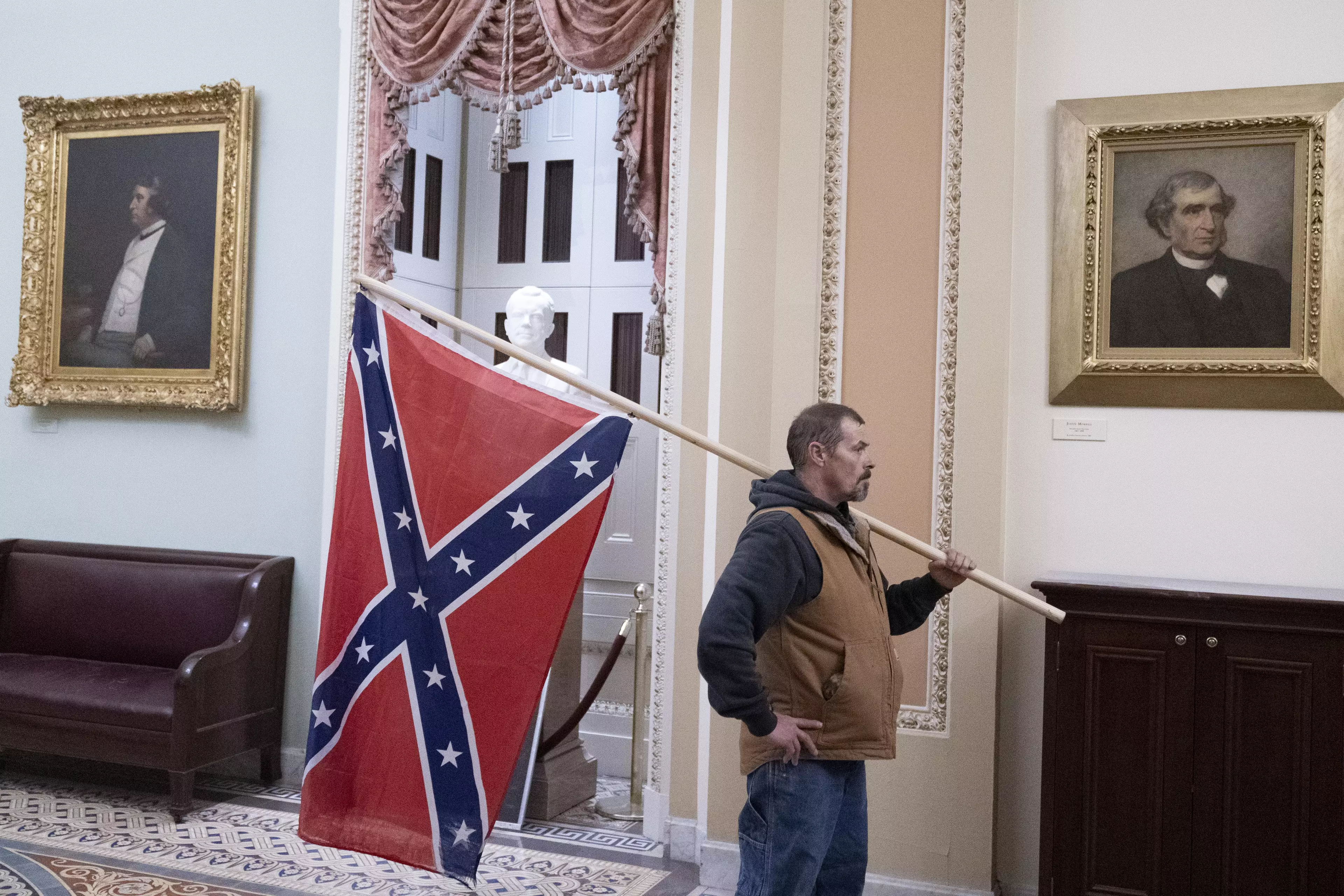 A rioter stands with the Confederate flag in the Capitol.