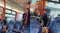 女人在男人坐在她旁边的几乎空的公共汽车旁边防守