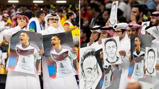 Fans hold pictures of Mesut Ozil while covering mouths during Germany vs Spain game