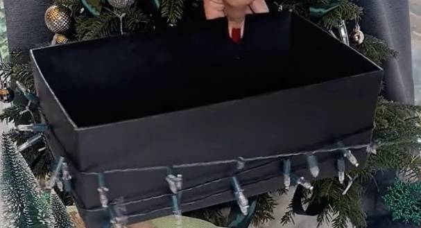 Once you've wrapped the lights around, cut a small slit in the box so you can store the battery/power pack inside. Credit: TikTok/@tanyahomeinspo