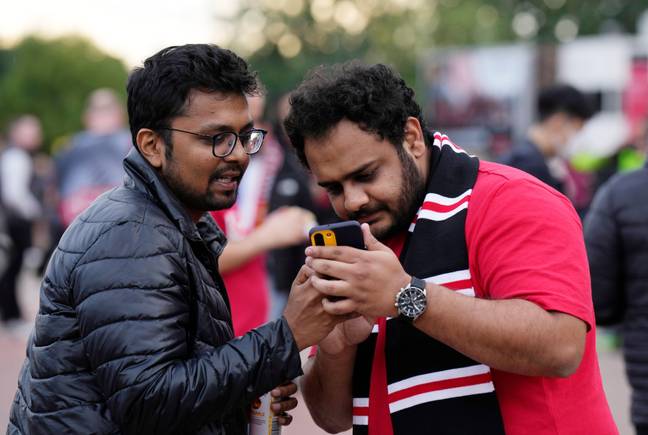 Fans outside Old Trafford learn of the news on their phones. Image: Alamy