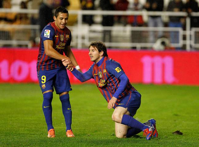 Messi is helped from the ground by Alexis Sanchez. (Image Credit: Alamy)