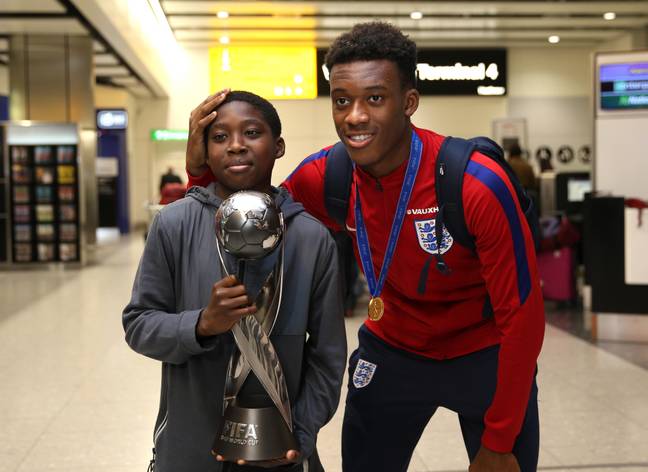 Callum Hudson-Odoi poses with his brother and the World Cup at Heathrow airport. Image credit: Alamy