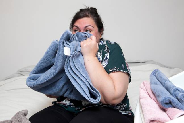 Woman smelling towels (Credit: Alamy)