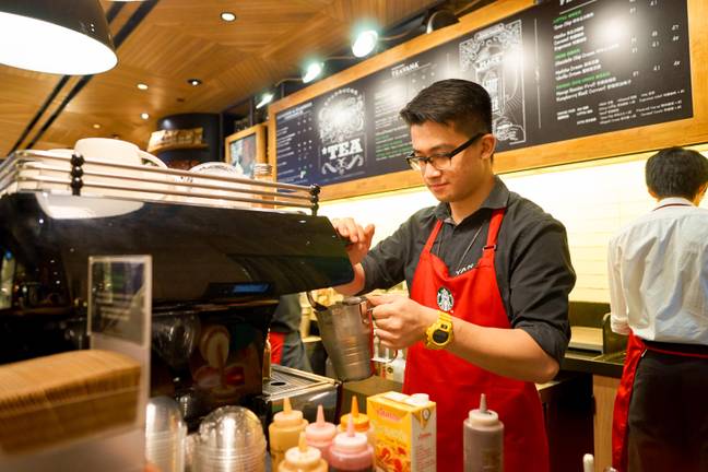 A Starbucks worker in a red apron. Credit: Heorshe / Alamy Stock Photo