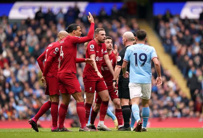 Liverpool players surround the referee following his decision not to book Rodri. (PA images)