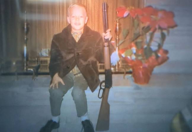 Joe Exotic as a child posing with a rifle (Credit: Netflix)