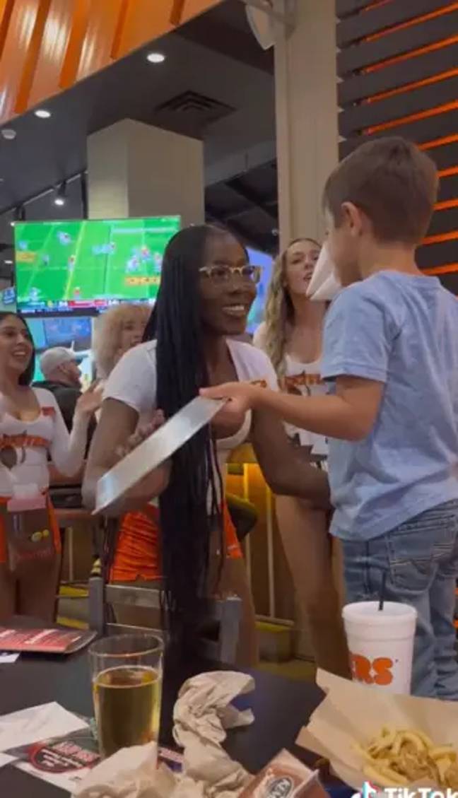 Whether you're for or against it, the Hooters staff were making the boy feel very comfortable as the five-year-old is seen smiling from ear-to-ear. Credit: TikTok/@darbyallison19