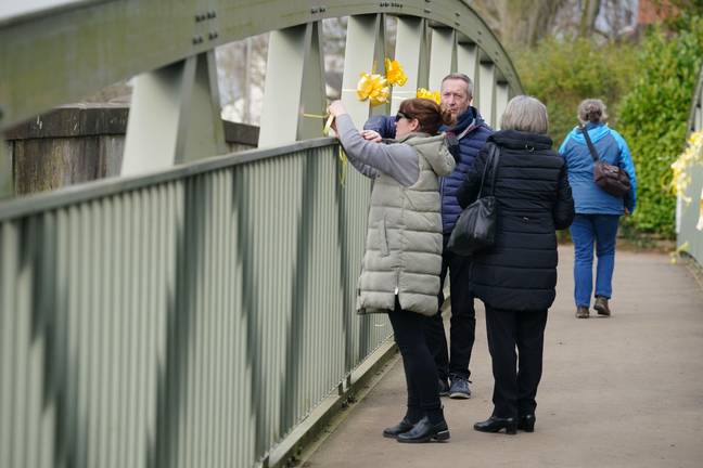 Nicola Bulley's sister, Louise Cunnigham (left), with her mother and father-in-law, ties a yellow ribbon to a bridge over the River Wyre. Credit: PA Images / Alamy Stock Photo