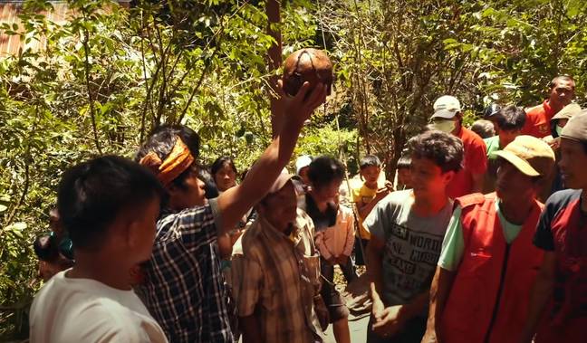 A Torajan man holds up the skull of his relative as part of the 'walking dead' ritual. Credit: YouTube/Fearless&amp;Far