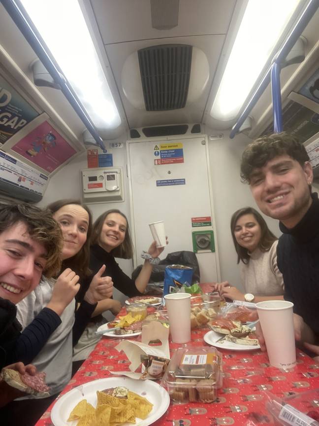 A group of students celebrated Christmas by taking their own dinner and dining table on the London tube. Credit: Kennedy News and Media