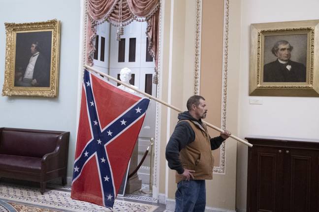 A rioter stands with the Confederate flag in the Capitol. Credit: PA