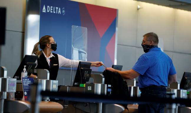 A ticketing agent for Delta Airlines hands a boarding pass to a passenger as he checks in for a flight in the main terminal of Denver International Airport. Credit: PA