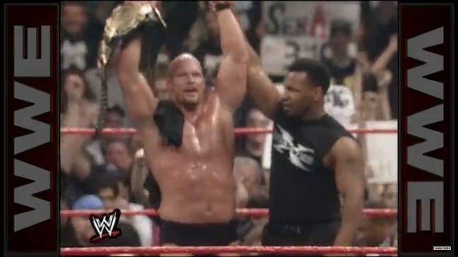 Mike Tyson raises Stone Cold Steve Austin's arm aloft after helping him to victory