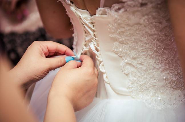 A woman putting on a wedding dress. Credit: Pexels / Oana Lupescu