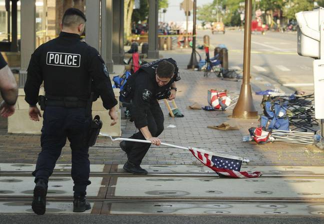 A police officer picks up a flag after Monday's mass shooting in Highland Park. Credit: Alamy