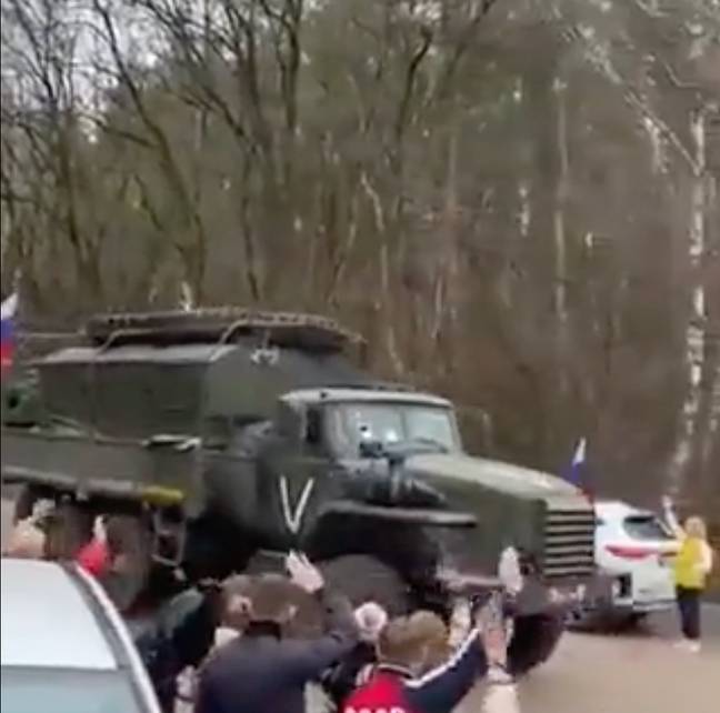 A Russian military convoy with a white painted symbol on its side, being waved into battle by passersby. Credit: @DefenceU/Twitter
