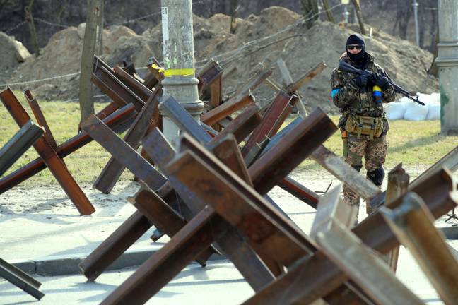 An armed Territorial Defence soldier stands guard at a roadblock, Kyiv, capital of Ukraine. Credit: Alamy