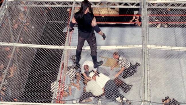 Not content with being thrown off a cell, Mankind returned to the match to be chokeslammed through a panel in the cell and to the mat below. Image: WWE.com
