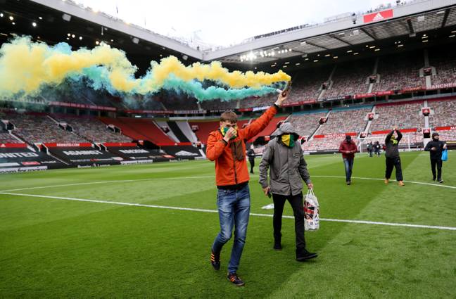 A fan with a flare on the Old Trafford pitch. (Image Credit: Alamy)