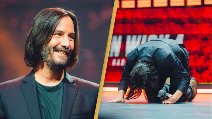 Keanu Reeves kneels on stage to fans as they give him standing ovation