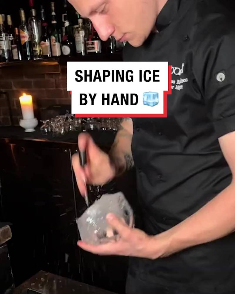 Bartender shapes ice by hand
