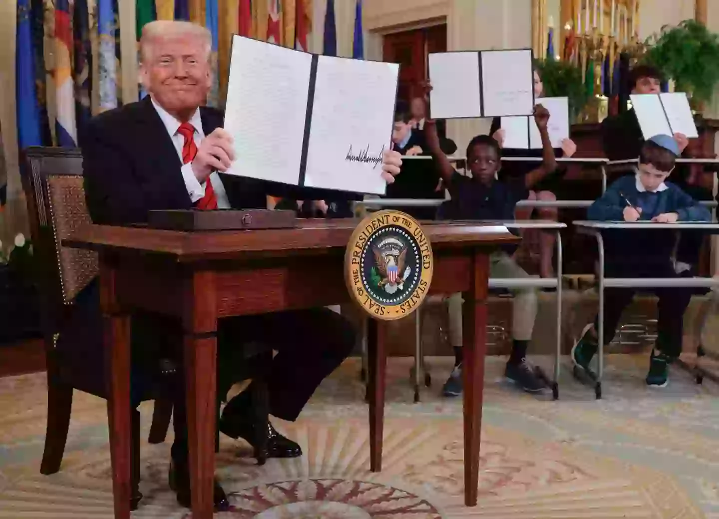 Trump was joined by a group of school kids as he signed the controversial order (Chip Somodevilla/Getty Images)