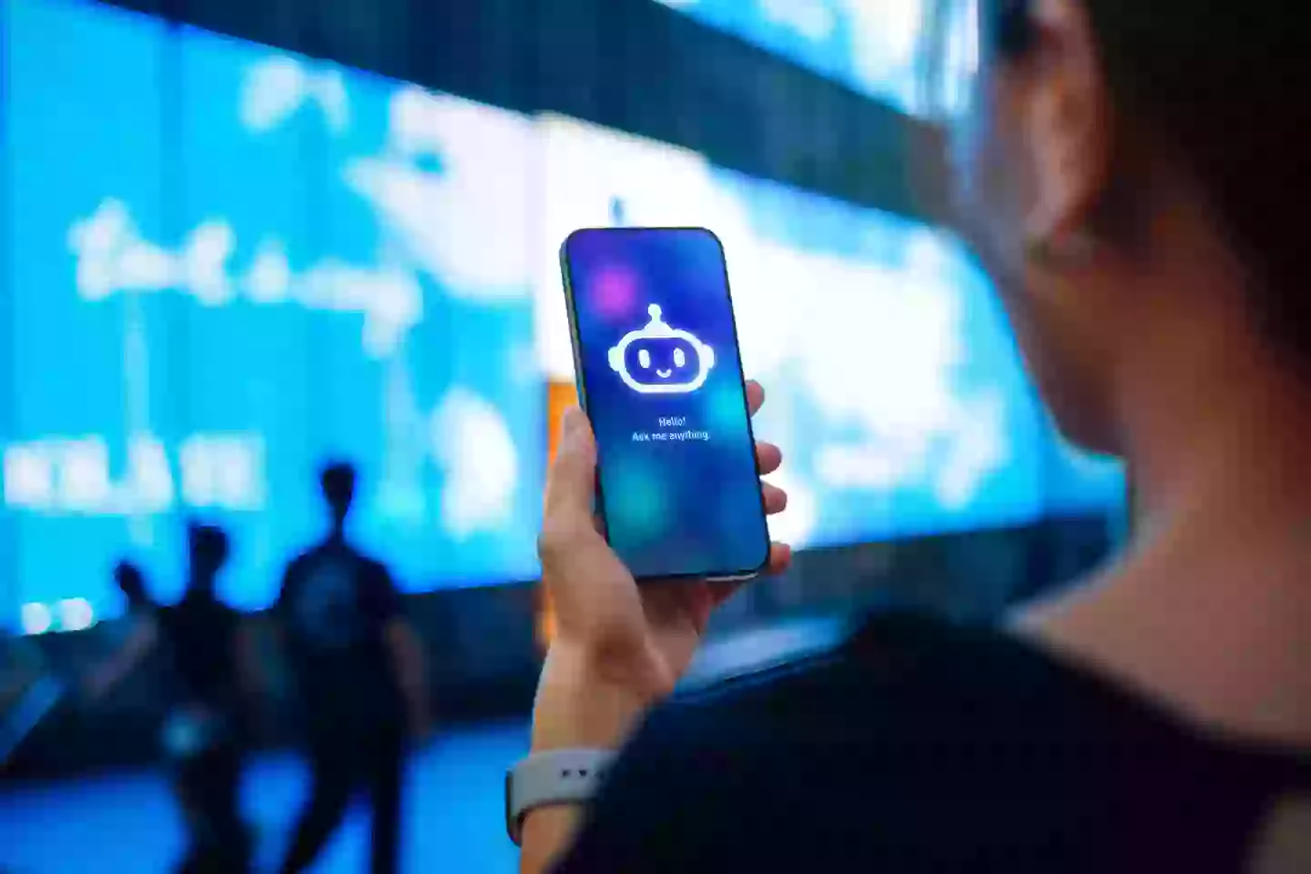 Woman standing against illuminated digital display on the street in city, speaking to virtual assistant (Getty Images)