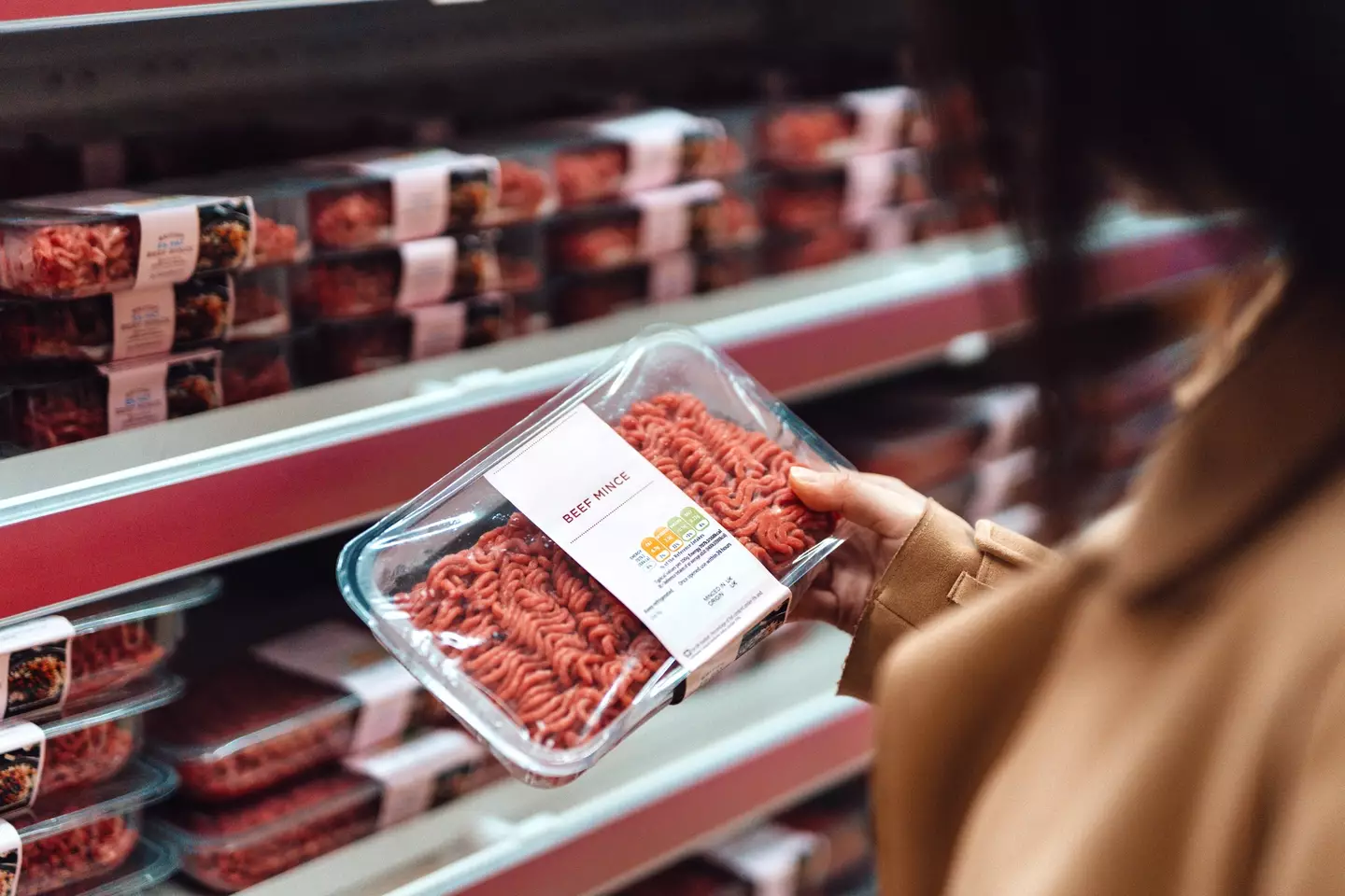 A woman considers a pack of beef mince - Oscar Wong via Getty Images