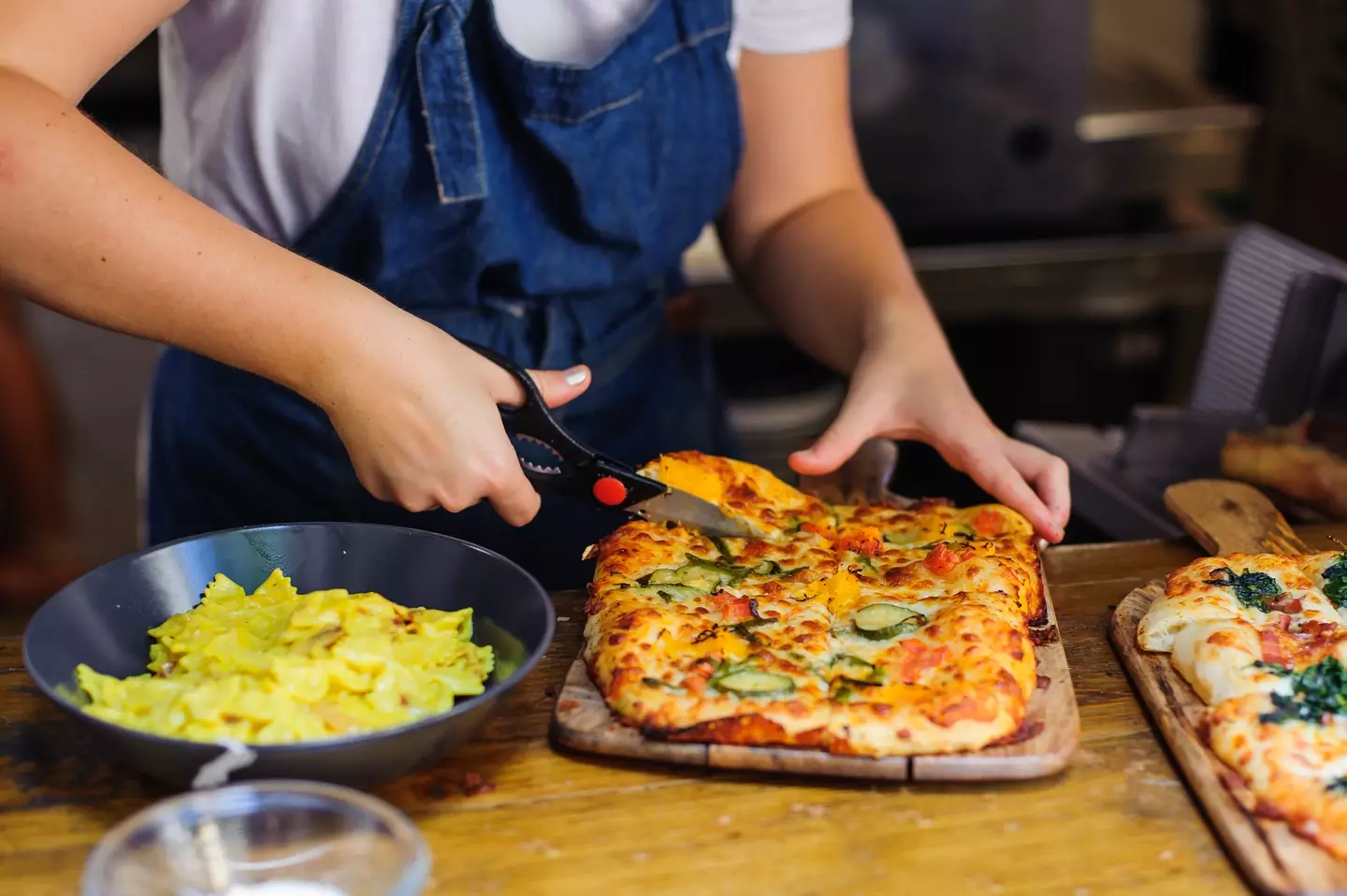 Man cutting pizza with scissors (Dariia Havriusieva/Getty Images)