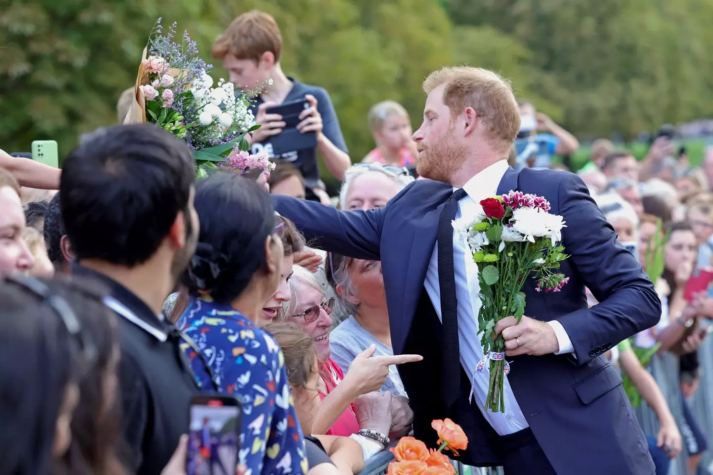 Harry can be seen collecting flowers from well wishers while greeting members of the public on Saturday evening in Windsor.