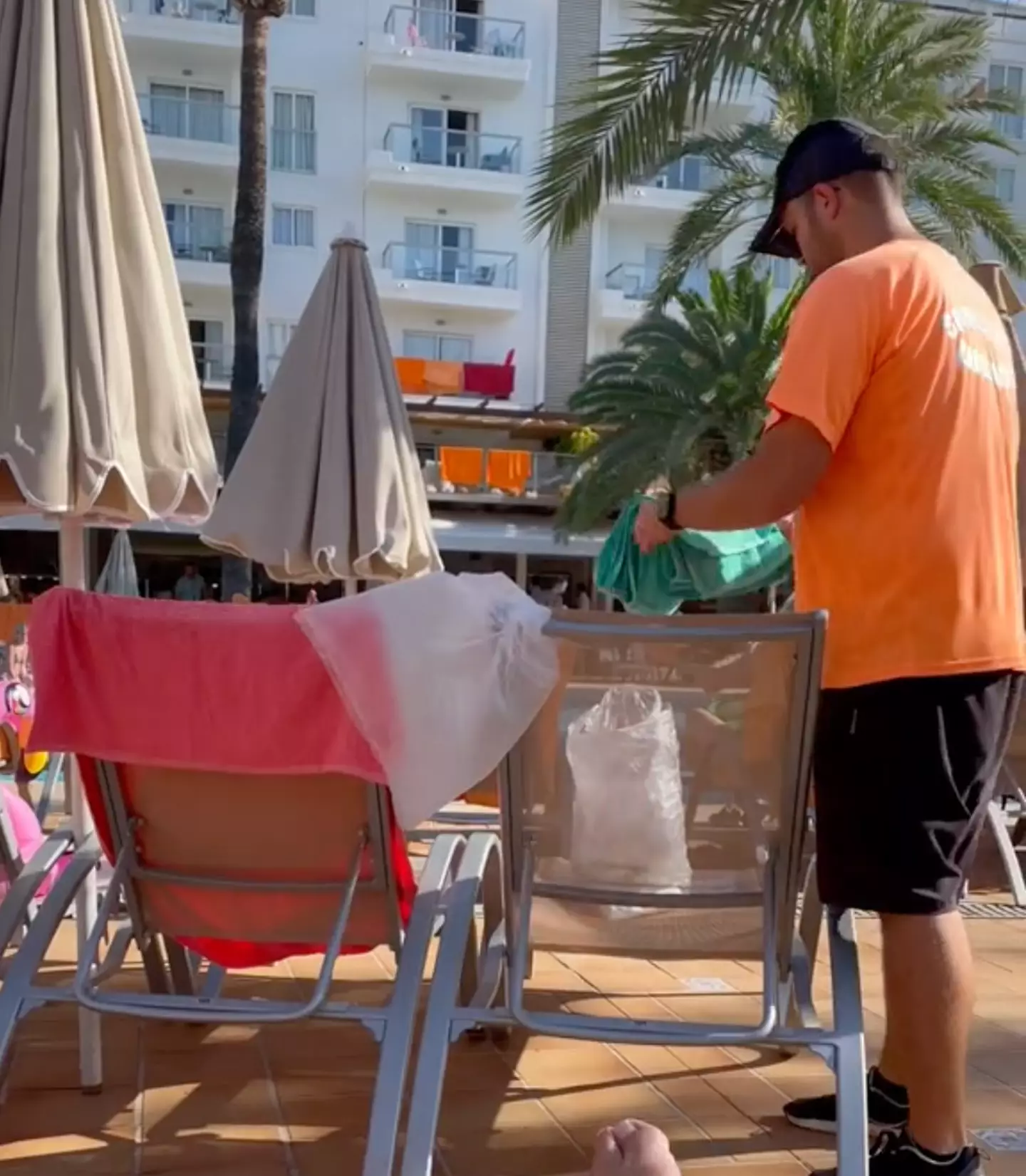 The hotel employee removed the towels from the unoccupied sunbeds.