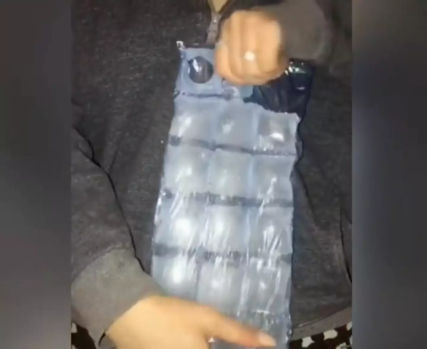 The woman freed the ice cubes by pulling the bag horizontally and vertically (
