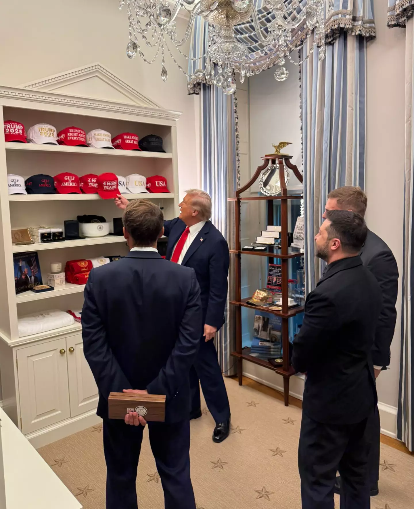 The President was snapped showing off his hat collection to Zelenskyy and Macron (Twitter/@MargoMartin47)