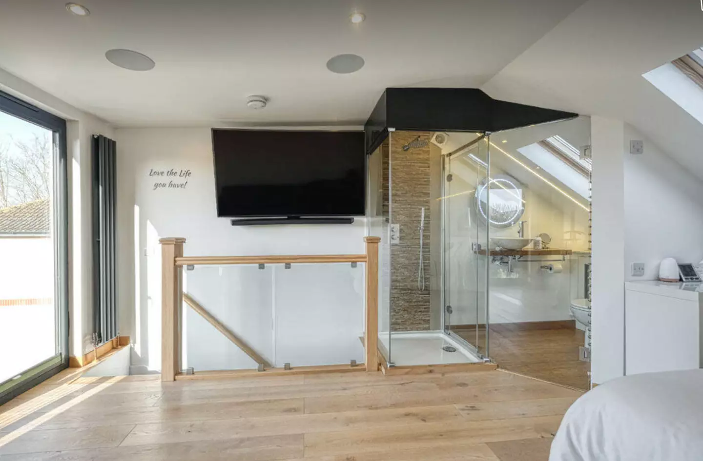 The shower and toilet is visible due to clear glass walls (